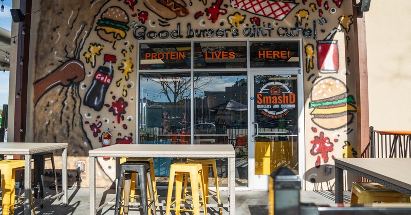 Restaurant entrance with vibrant mural with text Good burgers ain't cute! and PROTEIN LIVES HERE!