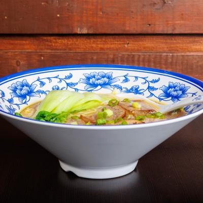 Asian noodle soup with bok choy and sliced meat.