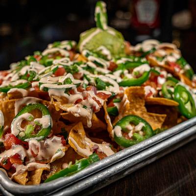 Loaded nachos with jalapenos, cheese sauce, salsa, and guacamole.