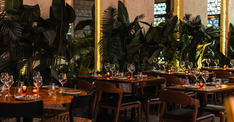 Beautifully designed interior dining area with tables set with wine glasses, plates, and candles