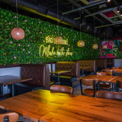 Interior with artificial green plant wall and neon sign on it.