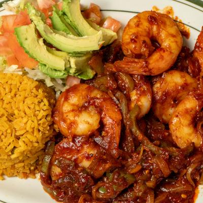 Shrimp in red sauce served with rice, salad, and avocado slices.