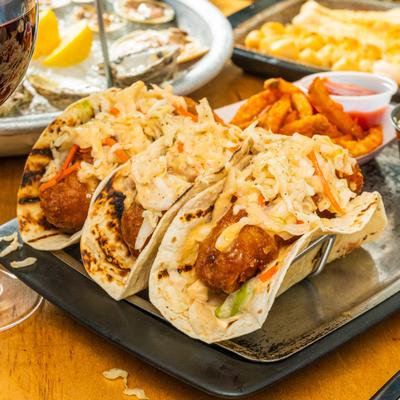 3 Baja Cod Tacos plate displayed with assorted food plates.