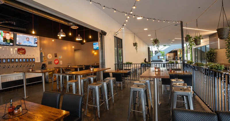 Exterior, patio, black metal railing, seating area, high and regular tables with chairs