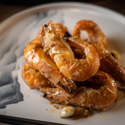 Seasoned shrimp piled on a round plate with garlic.