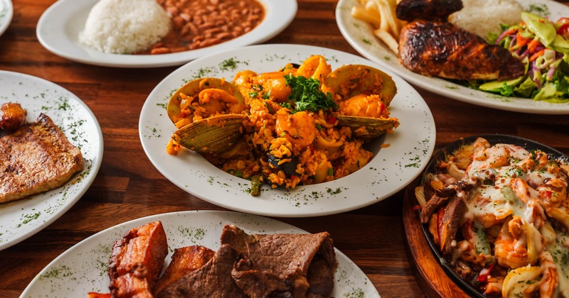 Multiple food plates spread on a wooden table