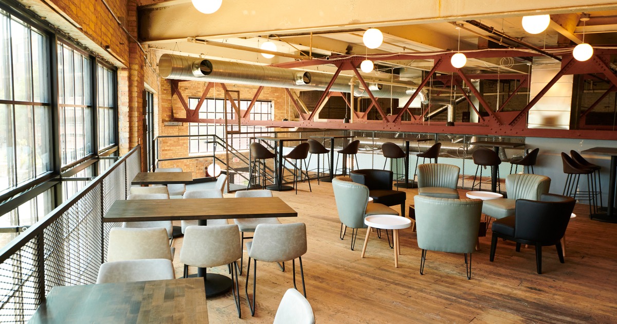 Industrial mezzanine lounge with modern seating, wooden floors, and large windows