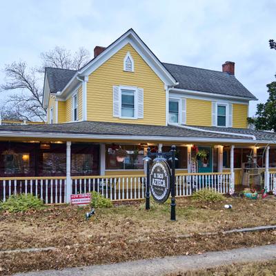 Yellow two-story house with a front porch and restaurant sign.