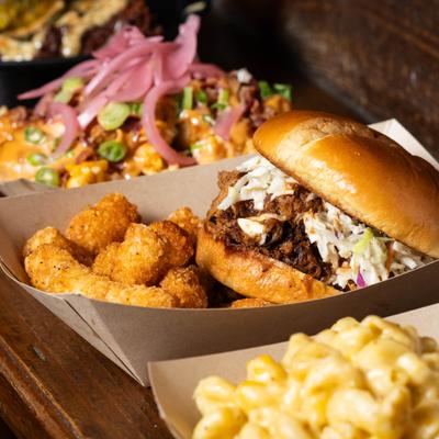 BBQ Sandwich with tater tots, served with other dishes.