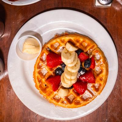 Belgium waffle topped with banana, mixed berries, and powdered sugar, served with maple butter.