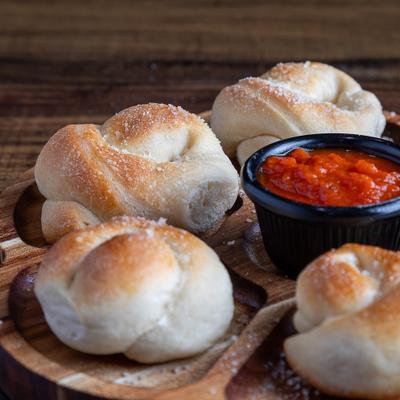Garlic rolls served on a wooden platter with a side of marinara.