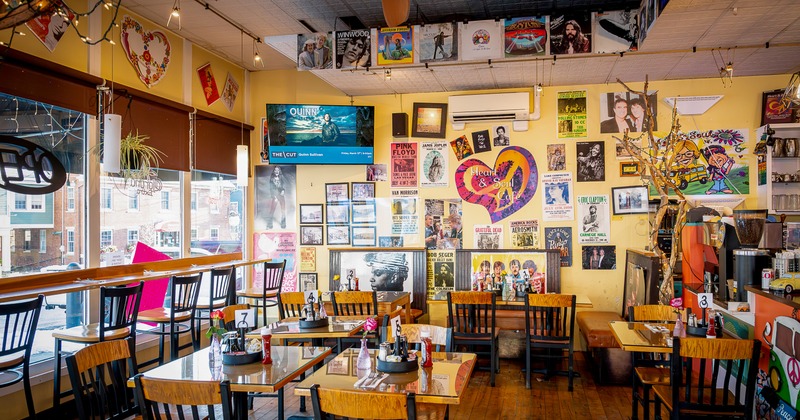 Interior seating area with yellow painted walls covered with framed photos and music posters
