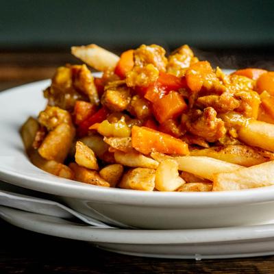 A plate of fries with chicken, gravy, and carrots.