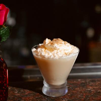 Cocktail in a martini glass, topped with whipped cream.
