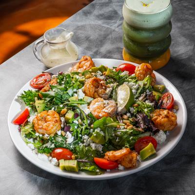 Mediterranean Shrimp Salad alongside a sressing and a drink.