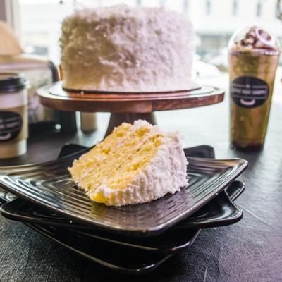 Slice of Coconut and Hibiscus Nectar Cake served alongside whole cake on a stand.