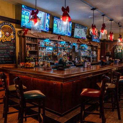 Sports bar interior with a wooden bar, holiday decor, and multiple TVs showing sports.