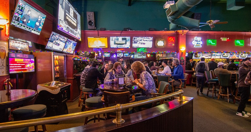 Interior space full of guests, tv sets on the walls