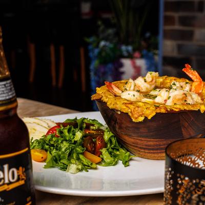 Stuffed mofongo with lobster and shrimp, served with a salad and a beer.
