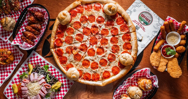 Pepperoni pizza surrounded by assorted appetizers
