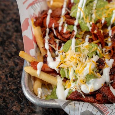 Loaded carne asada fries with guacamole, melted cheese, sour cream, and seasoned steak.