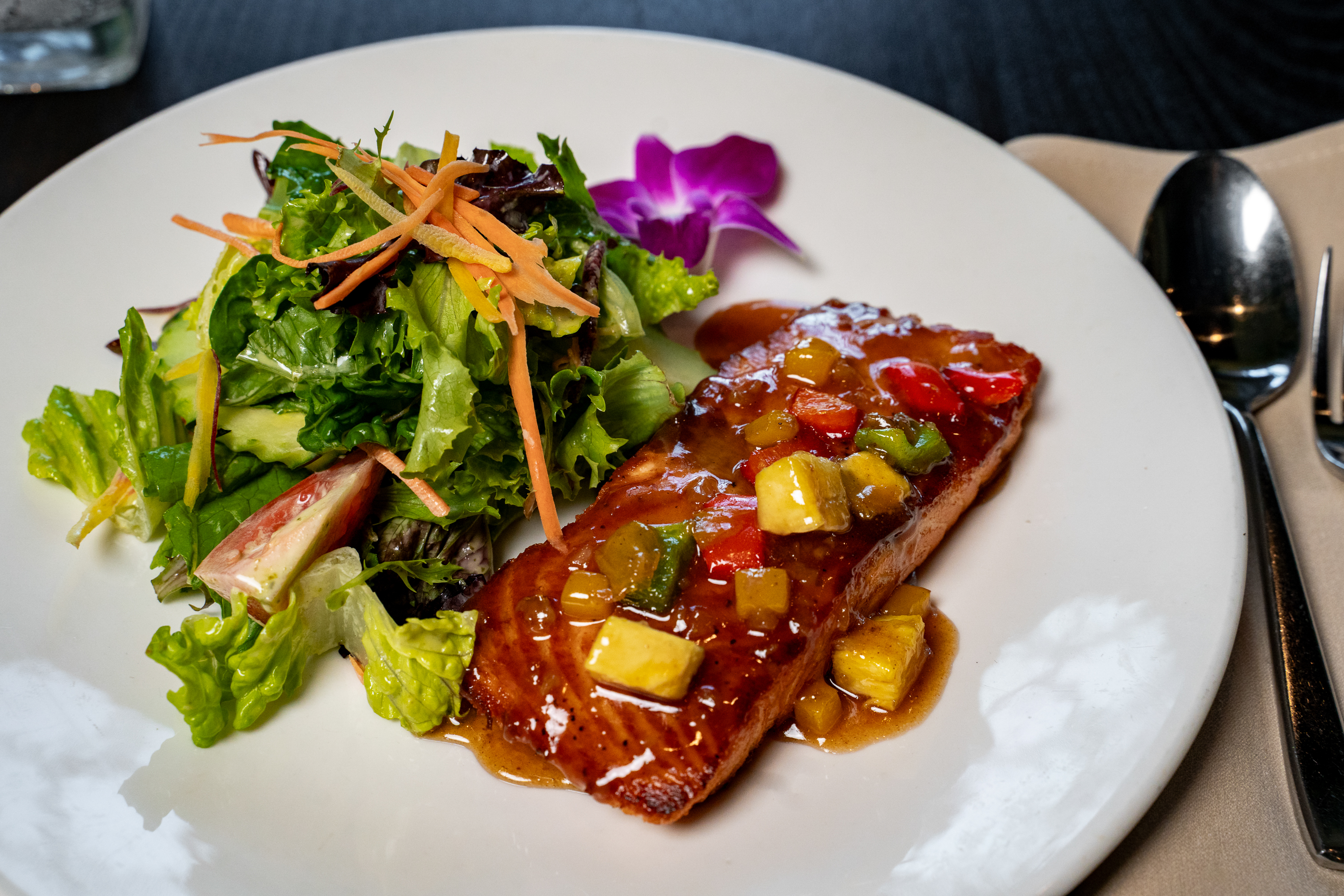 Mango Salmon served with a salad on the side, paired with a cocktail