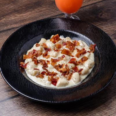 Gnocchi in cheese sauce, topped with bacon