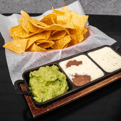 Trio Dip platter featuring guacamole, queso, and a bean-based dip served with chips.