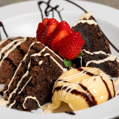 Brownie served with ice cream and sliced strawberries.
