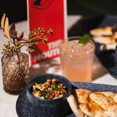 Baba ghanoush served with pita pieces on a platter, accompanied with a drink.