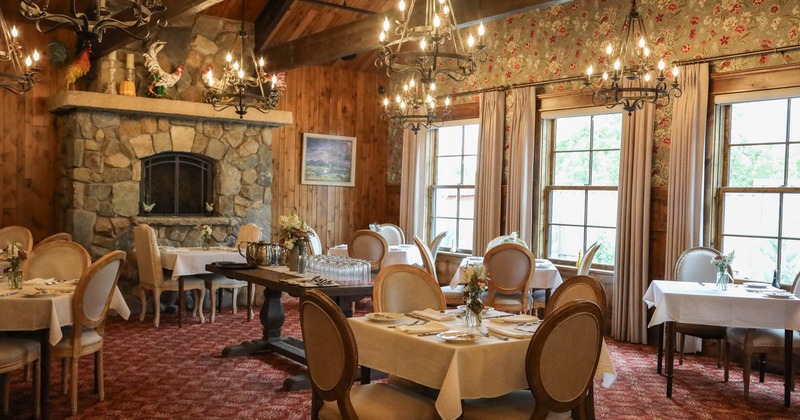 Interior, dining area, tables with chairs, stone built fireplace, carpet flooring