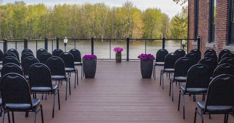 Exterior, terrace, wide deck with railing, event venue setup, lined up chairs, water view