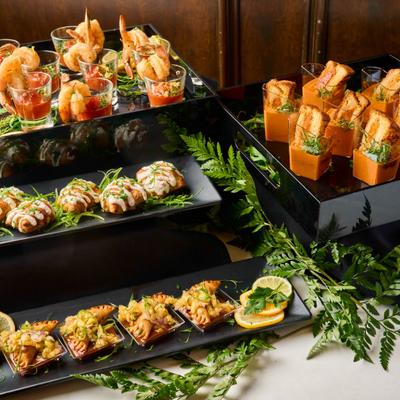 four different appetizers displayed on different levels, with greenery garnish on the table.