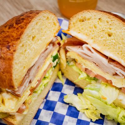 A close-up of a breakfast sandwich with turkey, lettuce, tomato, and egg.