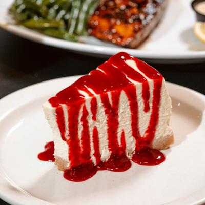 Cheesecake slice with a berry sauce drizzle.