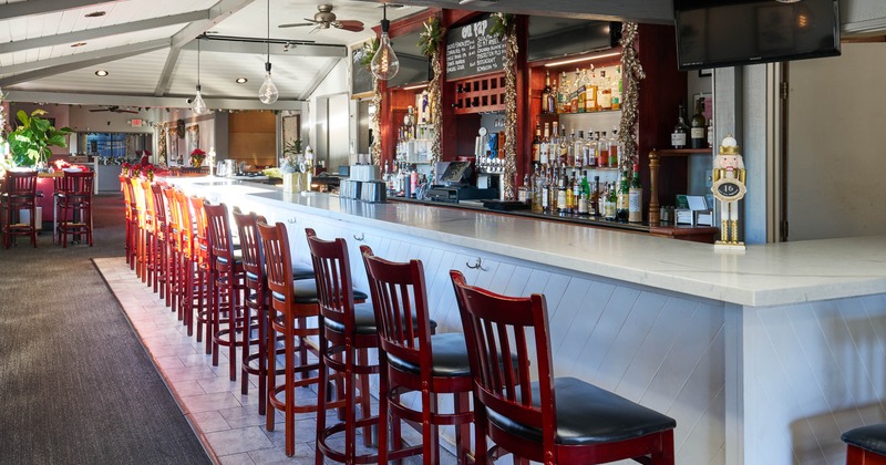 Modern bar with white countertop, red stools, and bottle-lined shelves