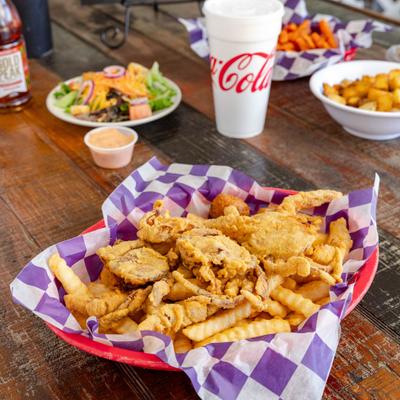 Basket with Fried Soft Shell Crab alongside other food items and a drink.