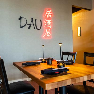 Wooden dining table beneath a neon restaurant sign with Japanese lettering.