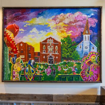 A painting in dining area, depicting a colorful rural scene.
