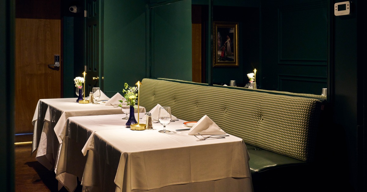 Intimate dining area with white tablecloths, folded napkins, and fresh flowers