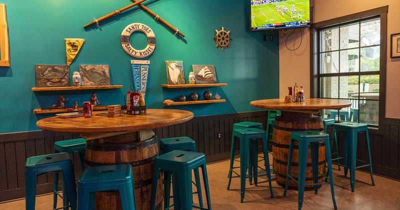 Interior, barrel tables and bar stools, tv screen in the corner