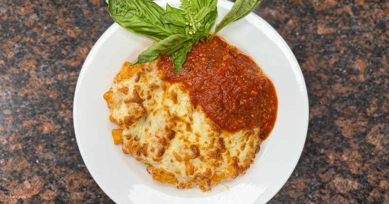 Baked pasta dish topped with melted cheese, tomato sauce and fresh basil