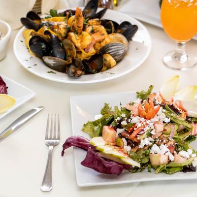 Walnut Salad served with an orange drink and a plate with mussels and shrimp.