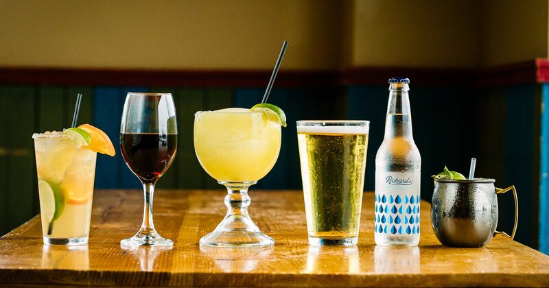 A line of drinks - wine, margarita, draft beer, bottled mineral water, copper cocktail cup.