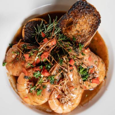 Large shrimp served over sauce with char-grilled bread, top view