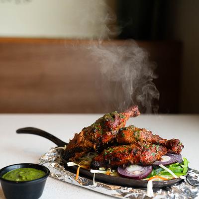 Tandoori Chicken and green chutney on a table.