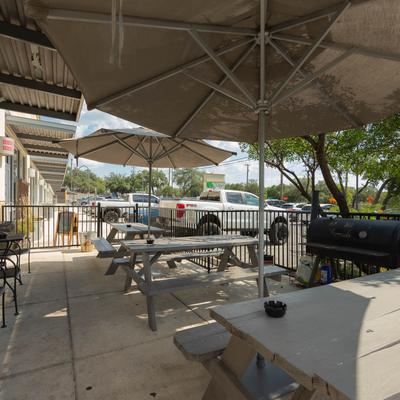 Outdoor patio with picnic tables, parasols, and a barbecue grill.