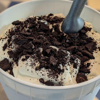 A cup of creamy vanilla ice cream topped with crumbled chocolate cookies.