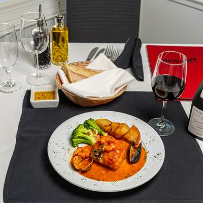 Mixed seafood in light red sauce, with broccoli and potatoes.