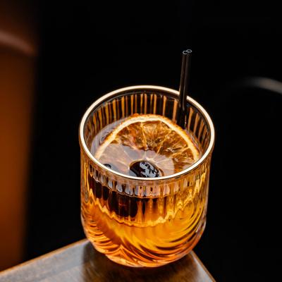 A cocktail garnished with a dried orange slice and cherries.